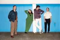 Vier Personen stehen vor einer blauen Garage