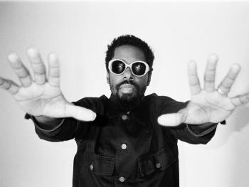 Person mit ausgestreckten Armen und offenen Händen vor weißem Hintergrund in schwarz-weißer Fotografie