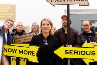 Die Kuratorin der Ausstellung steht mit einigen Künstlern im Schilderwald von Claus Richter