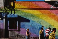 Menschen vor einer in Regenbogenfarben bemalten Mauer
