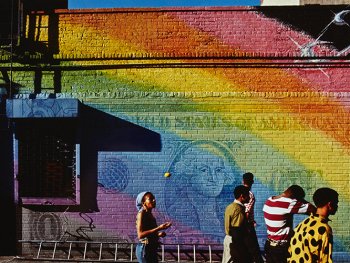 Menschen vor einer in Regenbogenfarben bemalten Mauer