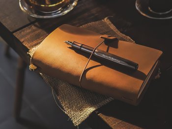 geschlossenes Notizbuch mit einem offenem Füller liegt auf einem Tisch