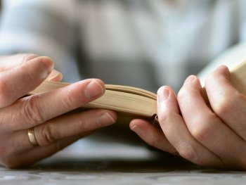 Zwei Hände halten ein aufgeschlagenes Buch