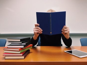 Foto: Pixabay
Ein Mensch hält ein aufgeschlagenes blaues Buch vor dem Gesicht