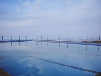 Foto: Lajos Keresztes, Marokko 0001, VG Bild-Kunst, Bonn 2026
Swimmingpool in dem sich der Himmel spiegelt und im Hintergrund das Meer zu sehen ist