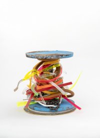 zeitgenössischer Pokal bestehend aus zwei blauen Metallscheiben, die eine Stange halten. Die Stange ist mit bunten Kunststoffbändern und einer Fahrradkette umwickelt.