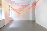 Zwei Fischernetze in Orange und Gelb sind in einem Raum von Wand zu Wand gespannt.