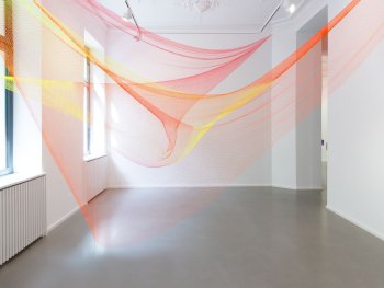 Foto: Courtesy Rana Begum and Galerie Chrisitan Lethert, Köln; Foto: Luisa Stricker
Zwei Fischernetze in Orange und Gelb sind in einem Raum von Wand zu Wand gespannt.