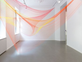 Copyright: Rana Begum, No. 1084 Net, 2023 Installationsansicht, Galerie Christian Lethert, Köln Zwei Fischernetze in Orange und Gelb sind in einem Raum von Wand zu Wand gespannt.