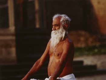 Foto: Lajos Keresztes, VG Bild-Kunst 2026
Mann mit langem, weißen Bart und nacktem Oberkörper im Yogasitz an einer Straße in Indien