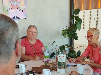 Personen sitzen am Tisch mit Handys vor sich