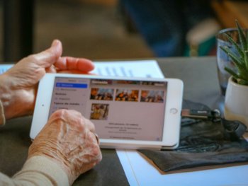 Copyright: Foto von Layla Ait Laaraj auf Unsplash Eine ältere Person hält ein Tablet und bekommt Hilfe bei der Nutzung.