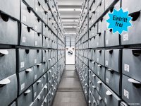 Enger Gang zwischen hohen Regalen mit grauen Archivboxen