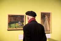 Ein Besucher betrachtet zwei Gemälde.