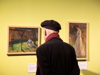 Ein Besucher betrachtet zwei Gemälde.