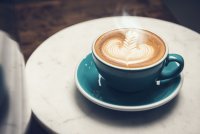 Dampfender Kaffee in blauer Tasse auf Untertasse und Tisch