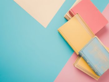 Foto: AdobeStock_889324411_c_dina
Stapel pastellfarbene Bücher liegen auf pastellfarbenem Untergrund
