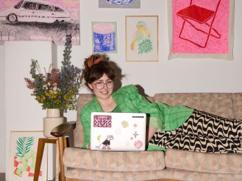 Pia Salzer auf ihrem Sofa vor ihren Werken