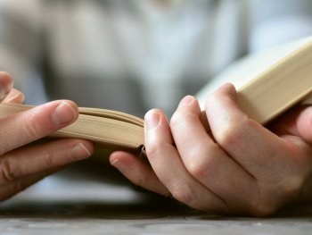 Zwei Hände halten ein aufgeschlagenes Buch