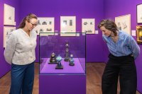 Zwei Besucherinnen stehen neben einer Glasvitrine und betrachten die ausgestellten Figuren aus Walter Moers Büchern.
