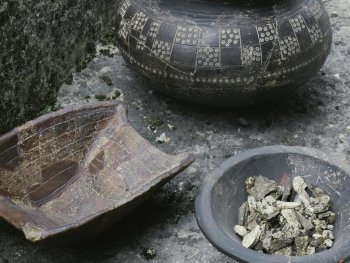 bemalte Tongefäße, eine Schale enthält verschieden große Gesteinsbrocken