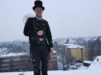 Copyright: Nether Schornsteinfeger steht auf einem Dach in einer verschneiten Stadt