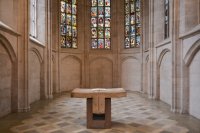 Ein Altar steht in der hell erleuchteten St. Martha Kirche mit farbigen Glasfenstern und Steinwänden.