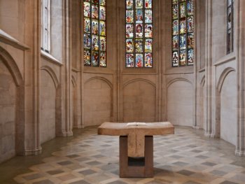 Ein Altar steht in der hell erleuchteten St. Martha Kirche mit farbigen Glasfenstern und Steinwänden.