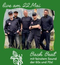 Ein Foto von fünf Personen in schwarzer Arbeitskleidung, die nebeneinander vor einer verwitterten Metallwand stehen. Oben links steht in weißer Schreibschrift „live am 22.Mai".