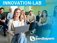 Innovation-Lab-Teaser von Nordbayern: Eine Person mit Laptop lächelt im Vordergrund, im Hintergrund eine Gruppe von Personen.