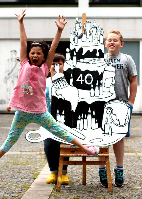 Ein springendes Kind vor einer gebastelten Torte mit der Aufschrift 40.