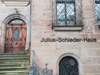 Fassade des Julius-Schieder-Hauses aus Sandstein mit Holztür, Treppenaufgang und schmiedeeisernem Tor.