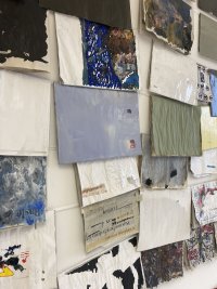 Collage aus zahlreichen Übermalungen von deutschen Zeitungsausschnitten – dicht nebeneinander an eine weiße Wand gehängt.