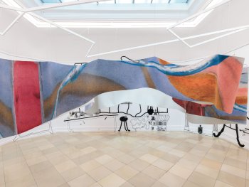Copyright: Henriette Grahnert, Rabbit Hole mit Meerblick, 2026 Fabian Treiber in Kooperation mit Ginster Bauer, Sorry for the carpet, 2026 © VG Bild-Kunst Bonn, 2026 für Henriette Grahnert Foto: Lukas Pürmayr Ein großformatiger, wellenförmig von der Decke hängendes bedruckter Teppich mit abstrakter Malerei in Blau, Orange und Rot hängt im Raum, der an den Wänden mit schwarzen Linienzeichnungen bemalt ist.