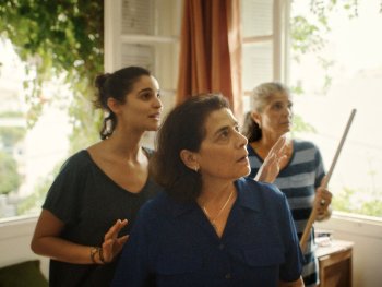 Copyright: Neue Visionen Filmverleih Drei Personen stehen in einem hellen Raum mit geöffneten Fenstern und blicken konzentriert nach oben, eine von ihnen hält einen langen Stab.
