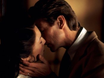 Copyright: Filmverleih Zwei Personen mit dunklem Haar nähern sich in warmer, gedimmter Atmosphäre für einen Kuss, wobei eine Person der anderen sanft die Hand ans Gesicht legt.