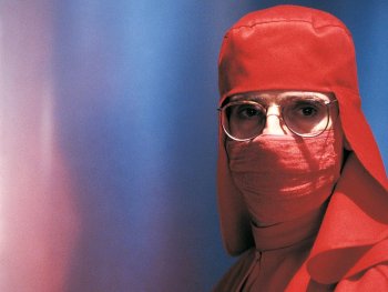 Copyright: Filmverleih
Person in einem vollständig roten Schutzanzug mit Haube, Gesichtsmaske und Brille blickt frontal in die Kamera.