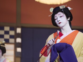 Copyright: SHUICHI YOSHIDAASP_2025 KOKUHO Film Partners
Person in traditioneller japanischer Kabuki-Kostümierung mit weißer Gesichtsschminke, gelbem Kimono und aufwendiger Kopfbedeckung hält einen Fächer.