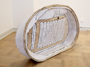 Großformatige Skulptur aus Pappelholz mit weißer Farbe in Form einer Blechdose, die auf dem Boden eines Galerieraums lehnt.