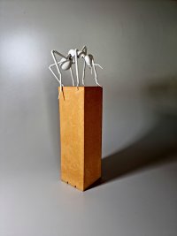 Skulptur einer Porzellan-Ameise, die auf einem Steinsockel steht.