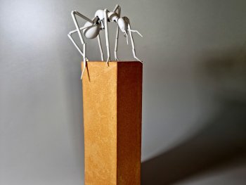 Skulptur einer Porzellan-Ameise, die auf einem Steinsockel steht.