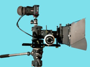 Filmkamera mit Mattebox und Studioleuchte auf türkisem Hintergrund