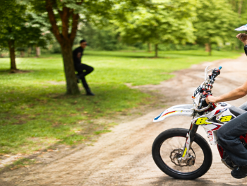 Copyright: Grandfilm; Vajda film
Person mit Motocross-Helm sitzt auf einem Motorrad mit Startnummer 189 auf einem Feldweg im Grünen, im Hintergrund stehen weitere Personen.
