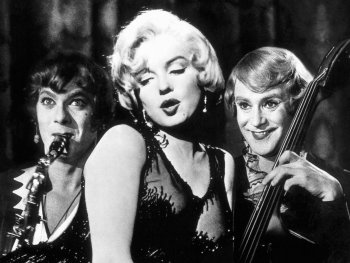 Copyright: MGM; Park Circus Schwarz-weiße Filmszene mit drei Personen im Glitzerkleid, eine spielt Saxofon, eine Kontrabass, während die Frau in der Mitte singt.