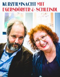 Kurzfilmnacht mit Egersdörfer & Schleindl: Ein Mann mit grauem Bart und eine lächelnde Frau mit roten Locken und Brille blicken in die Kamera.