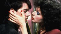 Zwei Personen in einer intimen Filmszene, die Frau hält das Gesicht des Mannes und beide nähern sich für einen Kuss.