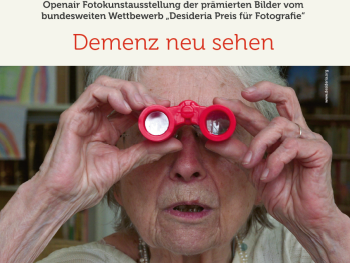 Ältere Person hält rote Spielzeugferngläser vor die Augen