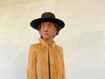 Foto: Clemens Heinl, VNP
Lebensgroße Holzskulptur einer Person mit schwarzem Hut und bemaltem Gesicht, der Körper mit unbehandeltem, grob strukturiertem Holz als Mantel gestaltet.