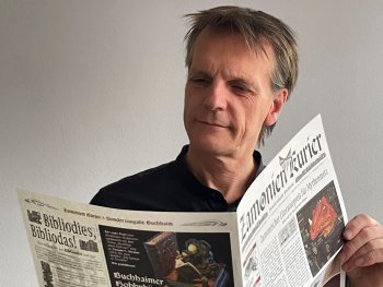 Ein Mann hält eine Zeitung in der Hand und liest darin.