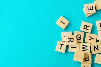 Durcheinander liegende Holzbuchstaben-Spielsteine auf türkisfarbenem Hintergrund.